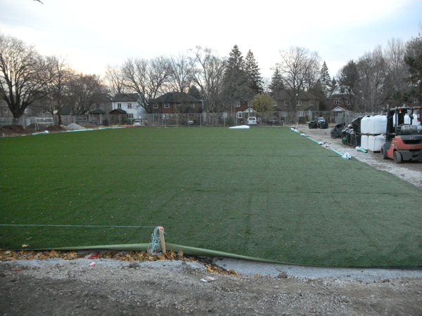 Almost completed installment of plastic carpet. Note the layers of aggregate and filter cloth along the edge (no crumb rubber infill).